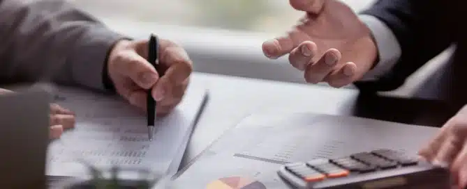 Entrepreneurs reviewing financial documents and calculations while comparing an acquisition loan with a traditional business loan for their next investment.