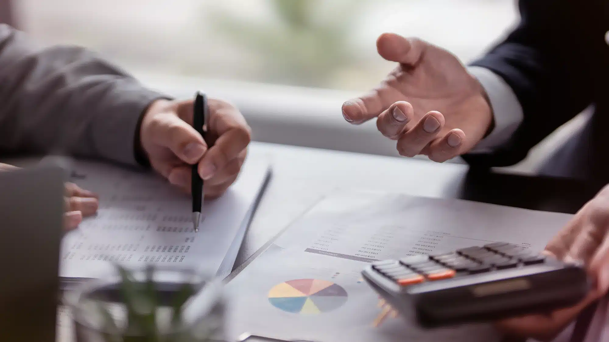 Entrepreneurs reviewing financial documents and calculations while comparing an acquisition loan with a traditional business loan for their next investment.